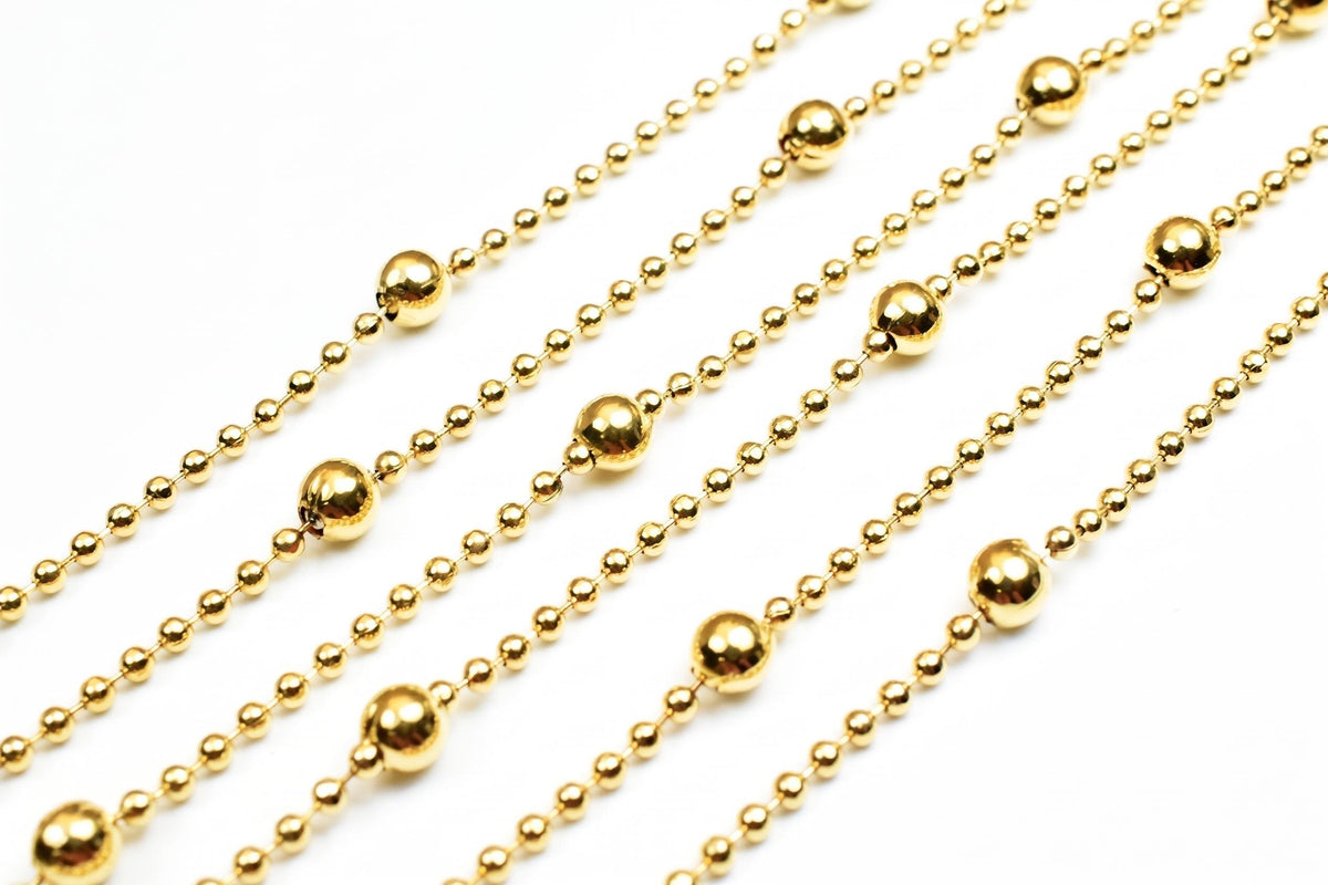 A close-up view of a collection of gold-colored metal bead necklaces arranged in a diagonal pattern.