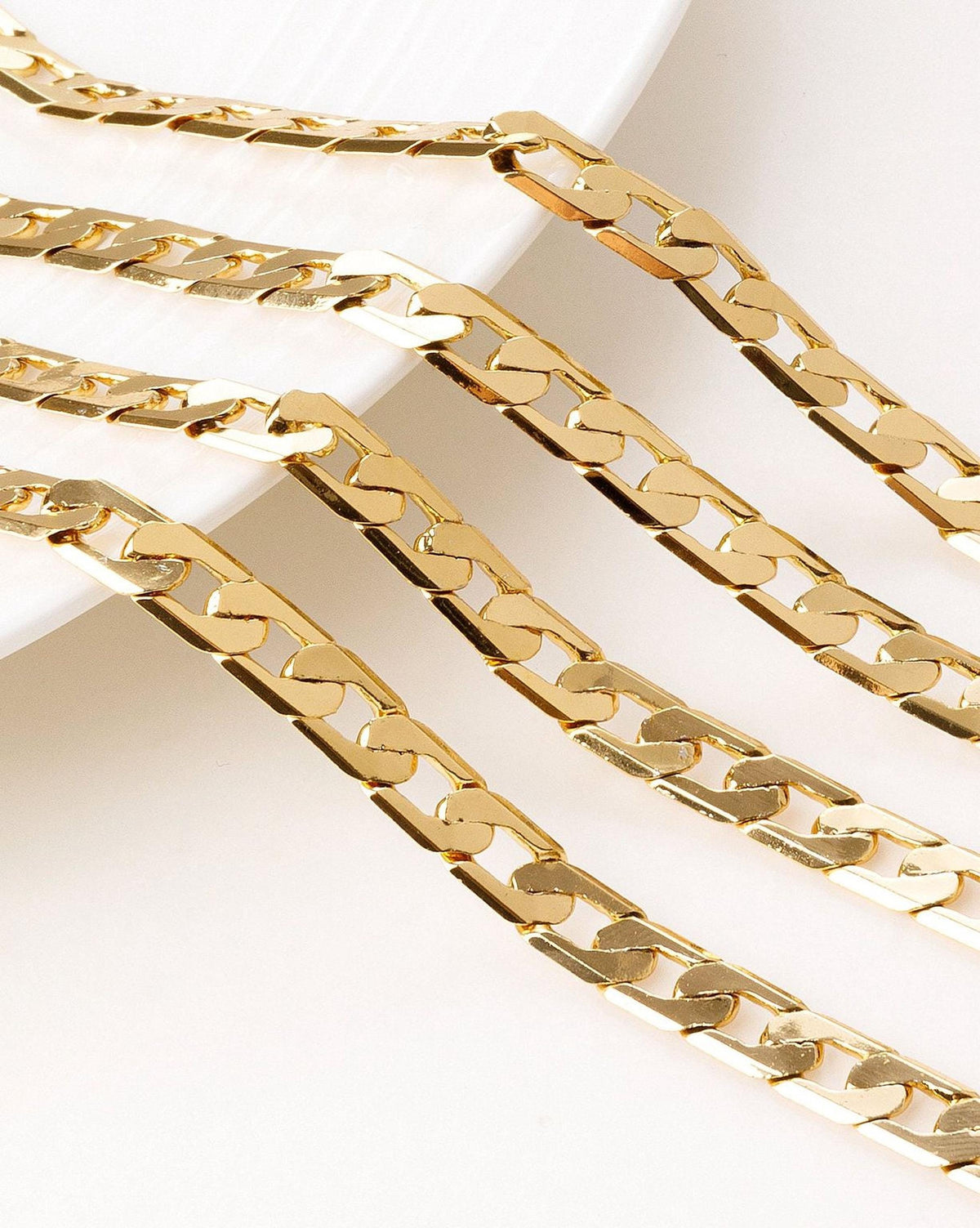 a close-up view of several gold-colored chain necklaces with a shiny, metallic appearance.
