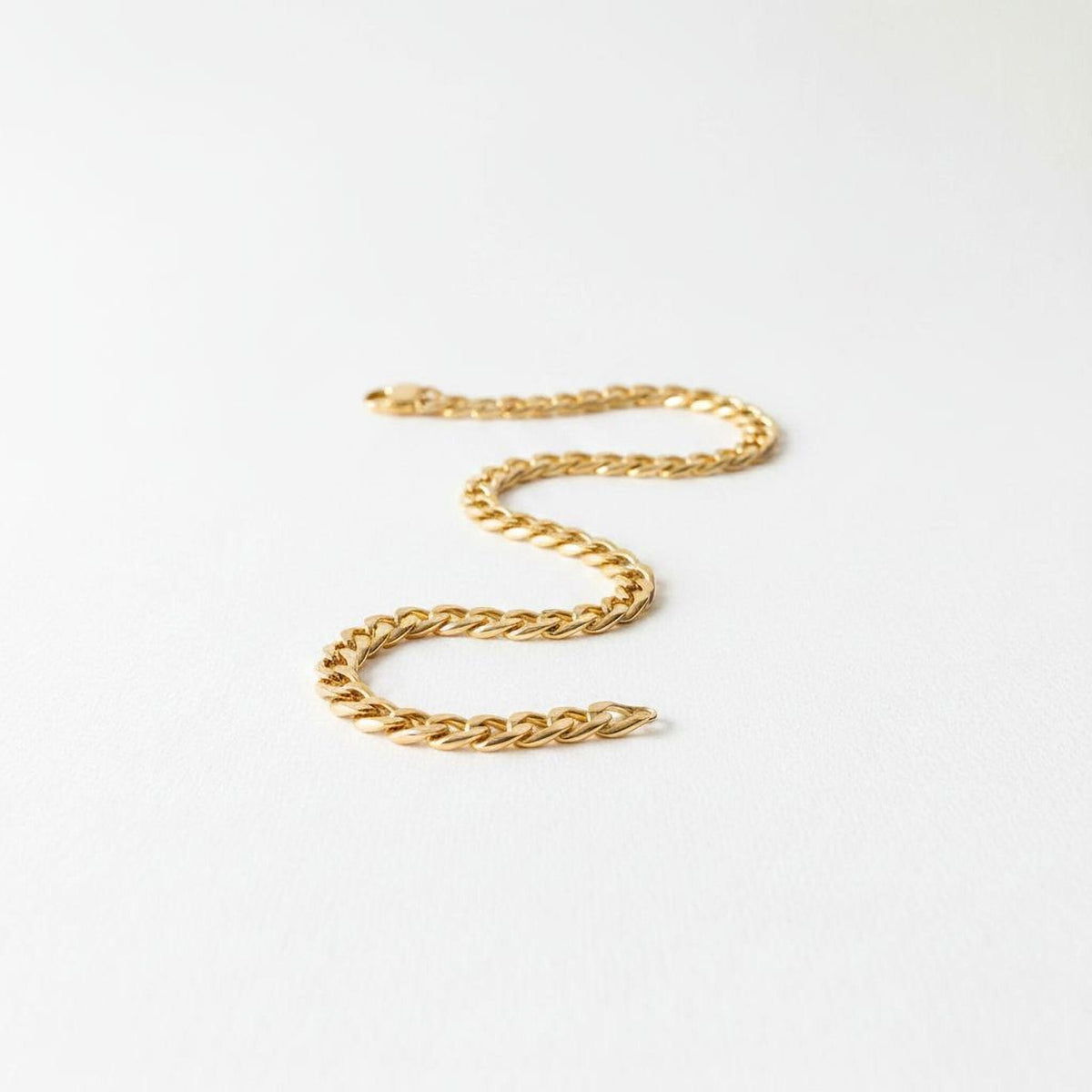 A gold chain necklace is shown against a white background.