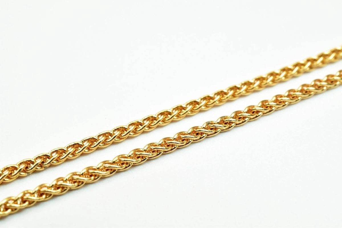 A close-up image of a gold chain necklace against a white background.