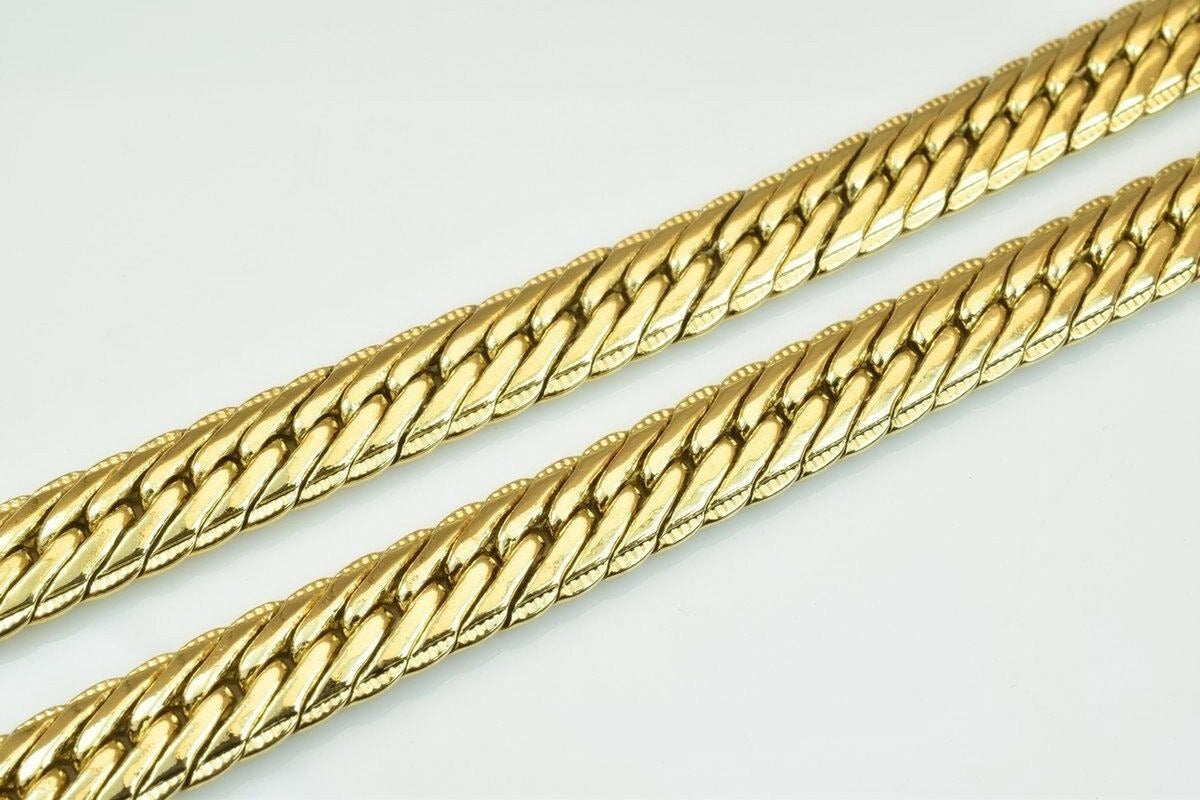 a close-up view of a gold-colored chain necklace with a distinctive interlocking pattern.