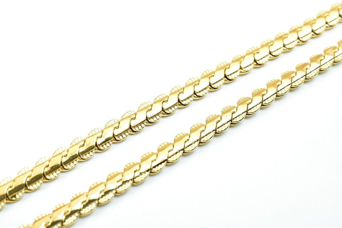 A close-up image of a gold chain necklace against a white background.