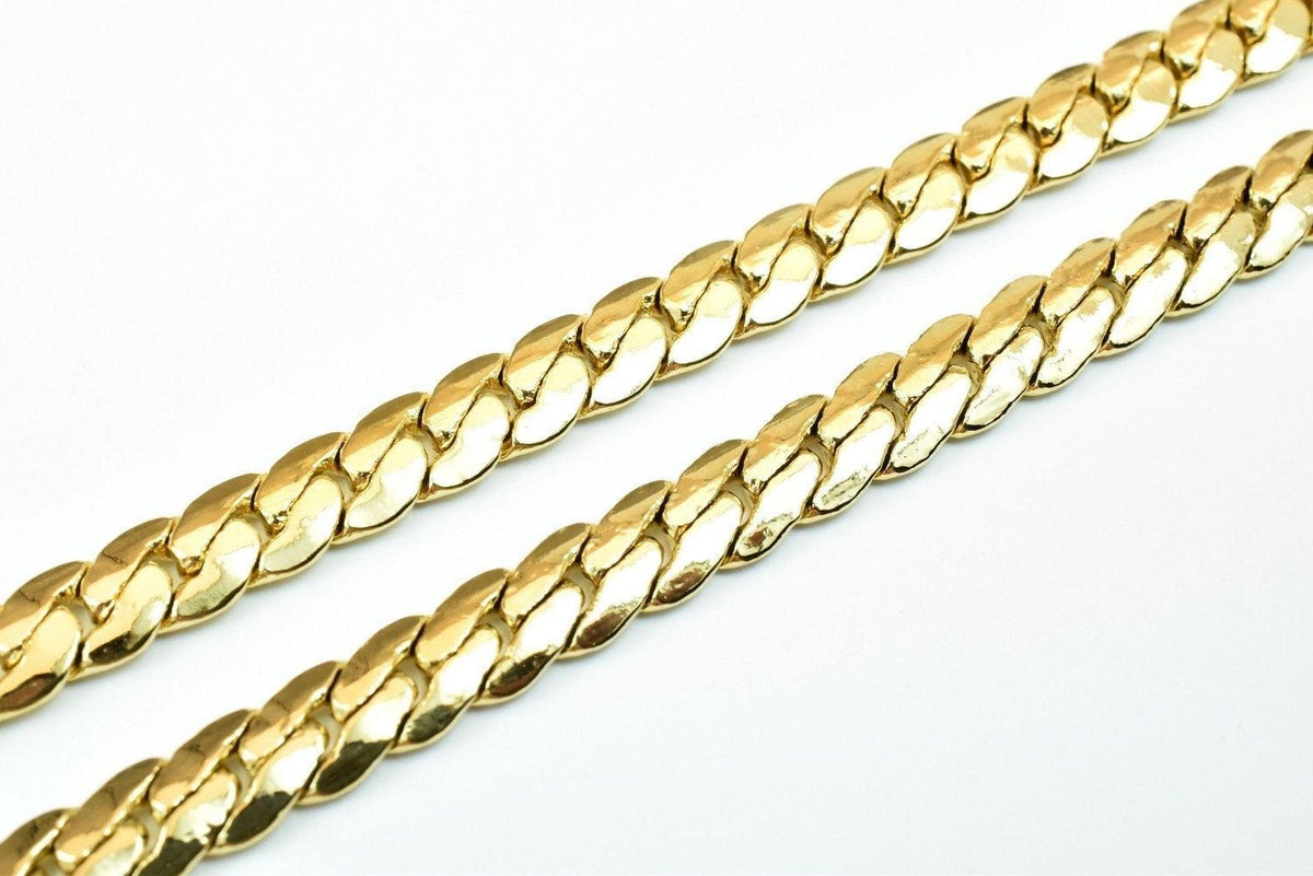 A close-up image of a gold chain necklace against a white background.