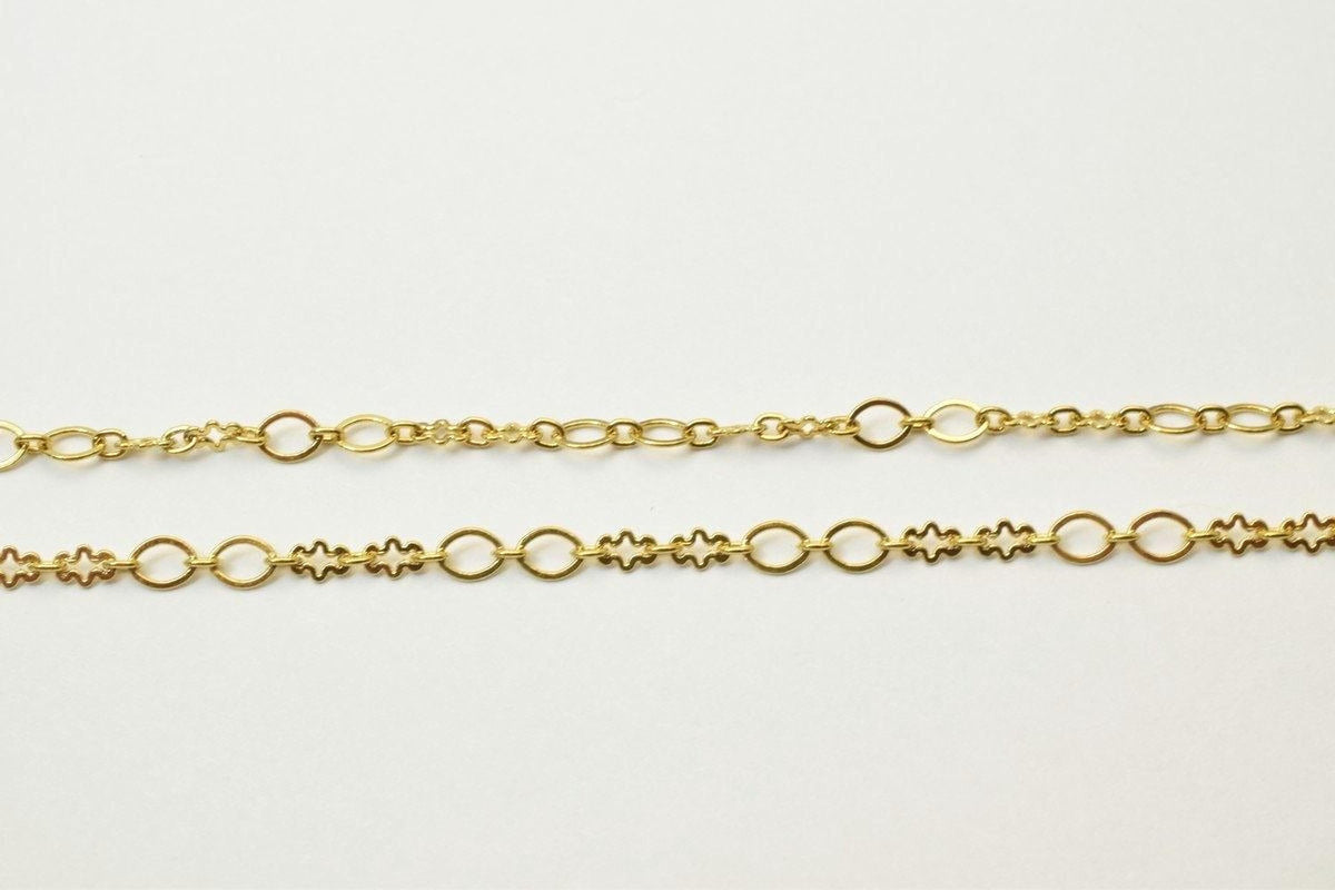 two gold-colored chain necklaces with various designs, including flowers and circles, laid out on a plain white background.