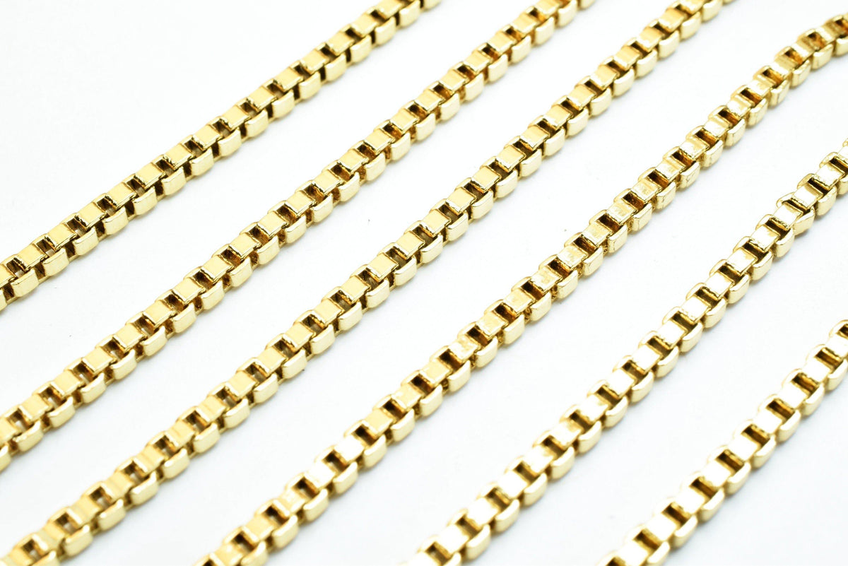 A collection of gold-colored metal chains arranged in a diagonal line against a white background.