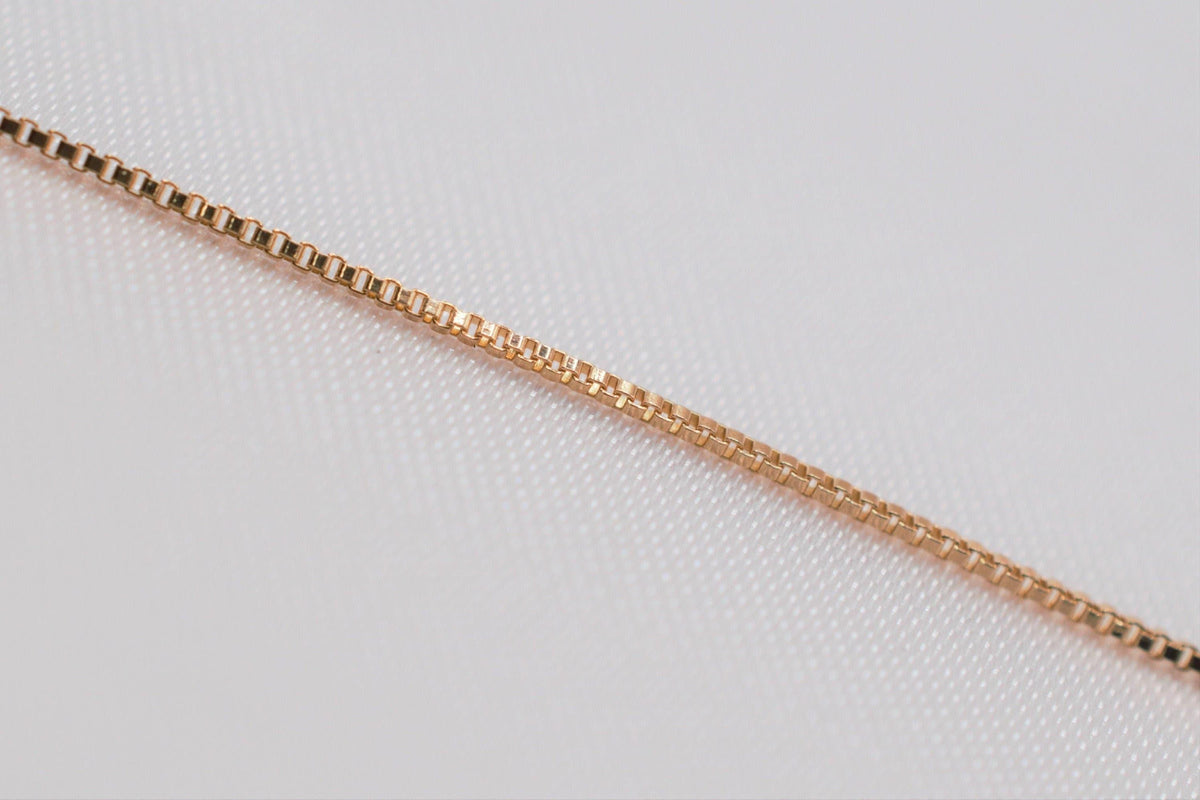 A close-up view of a gold-colored necklace chain against a white background.