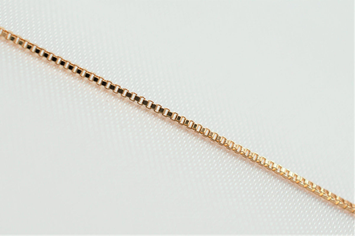 A gold-colored chain necklace is shown against a white background.