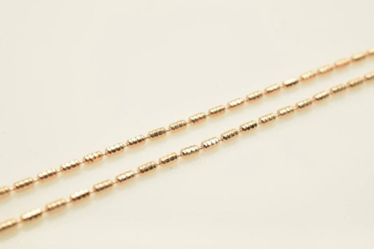 A close-up image of a gold-colored necklace with multiple strands of beads.