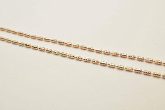 A close-up image of a gold-colored chain with small, round beads arranged in a repeating pattern.