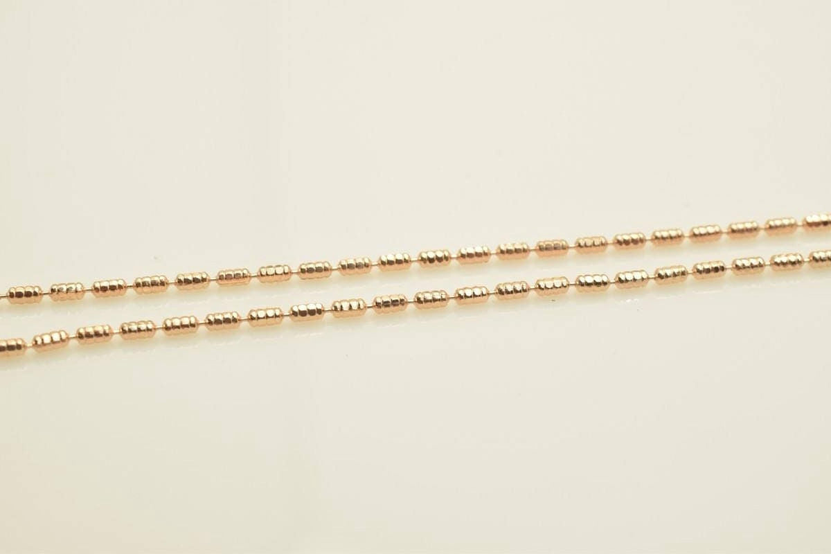 A close-up image of a gold-colored necklace with multiple strands of beads.