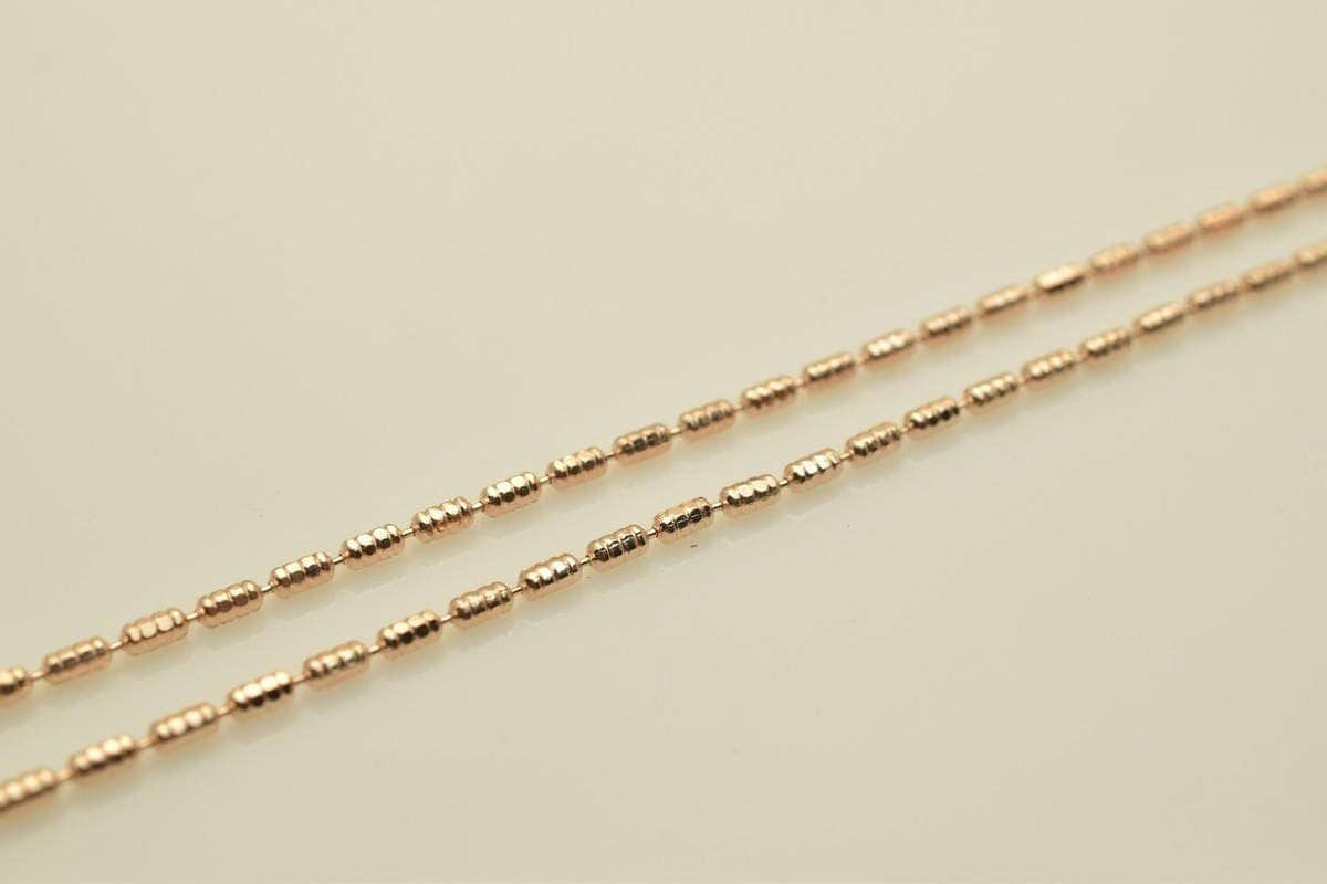A close-up image of a gold-colored necklace with multiple strands of small, round beads.