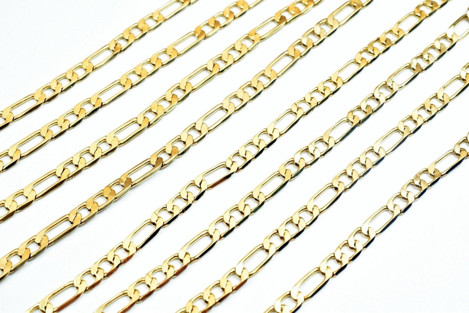 A collection of gold-colored metal chain necklaces arranged in a grid-like pattern against a white background.