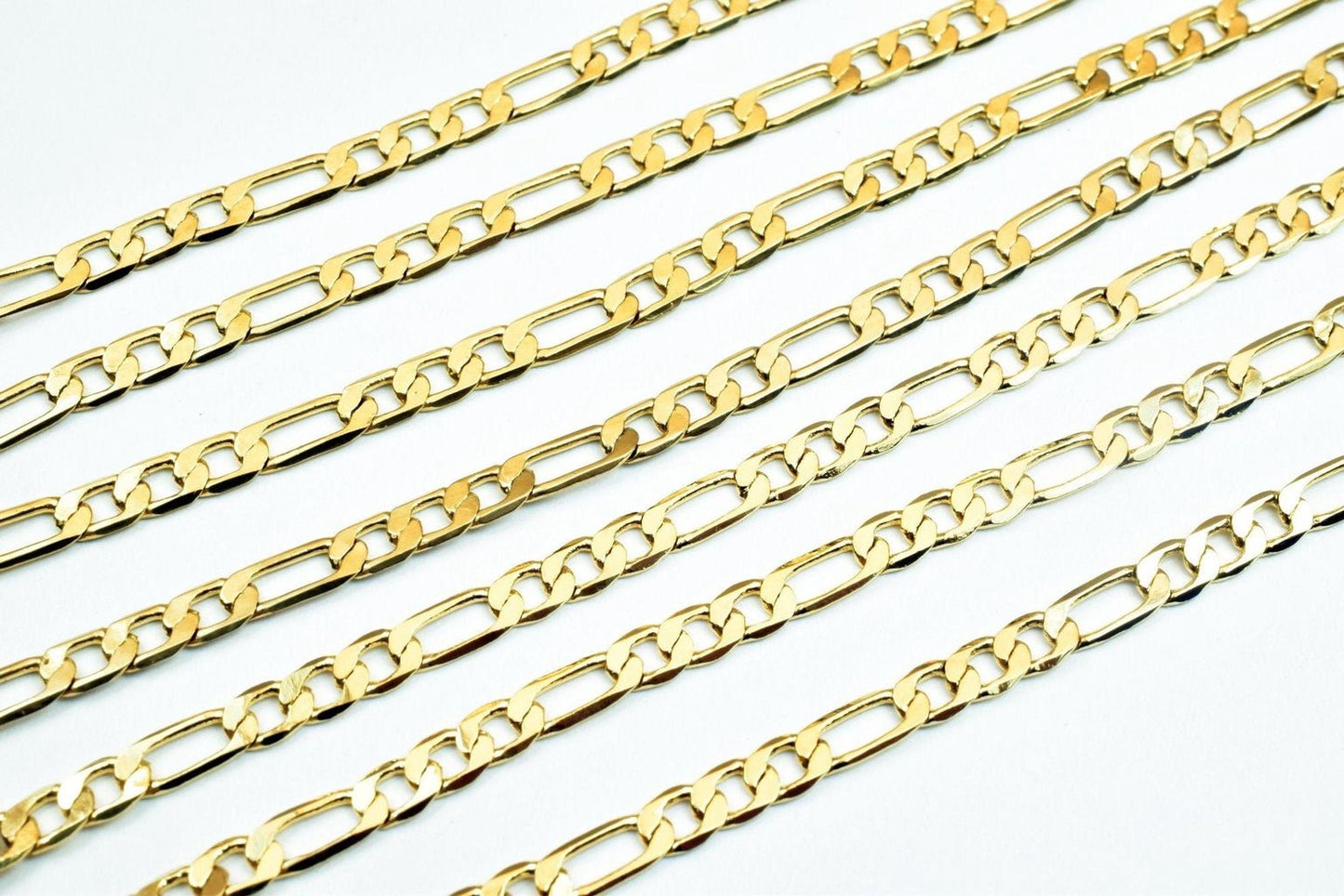 A collection of gold-colored metal chain necklaces arranged in a grid-like pattern on a white background.