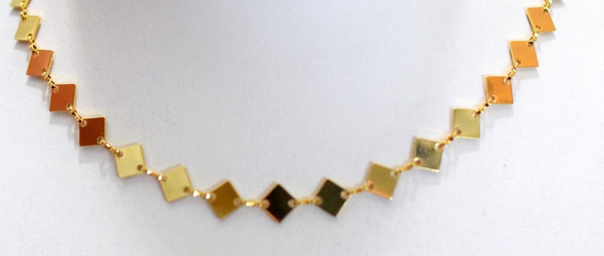 A close-up view of a gold necklace with diamond-shaped pendants.