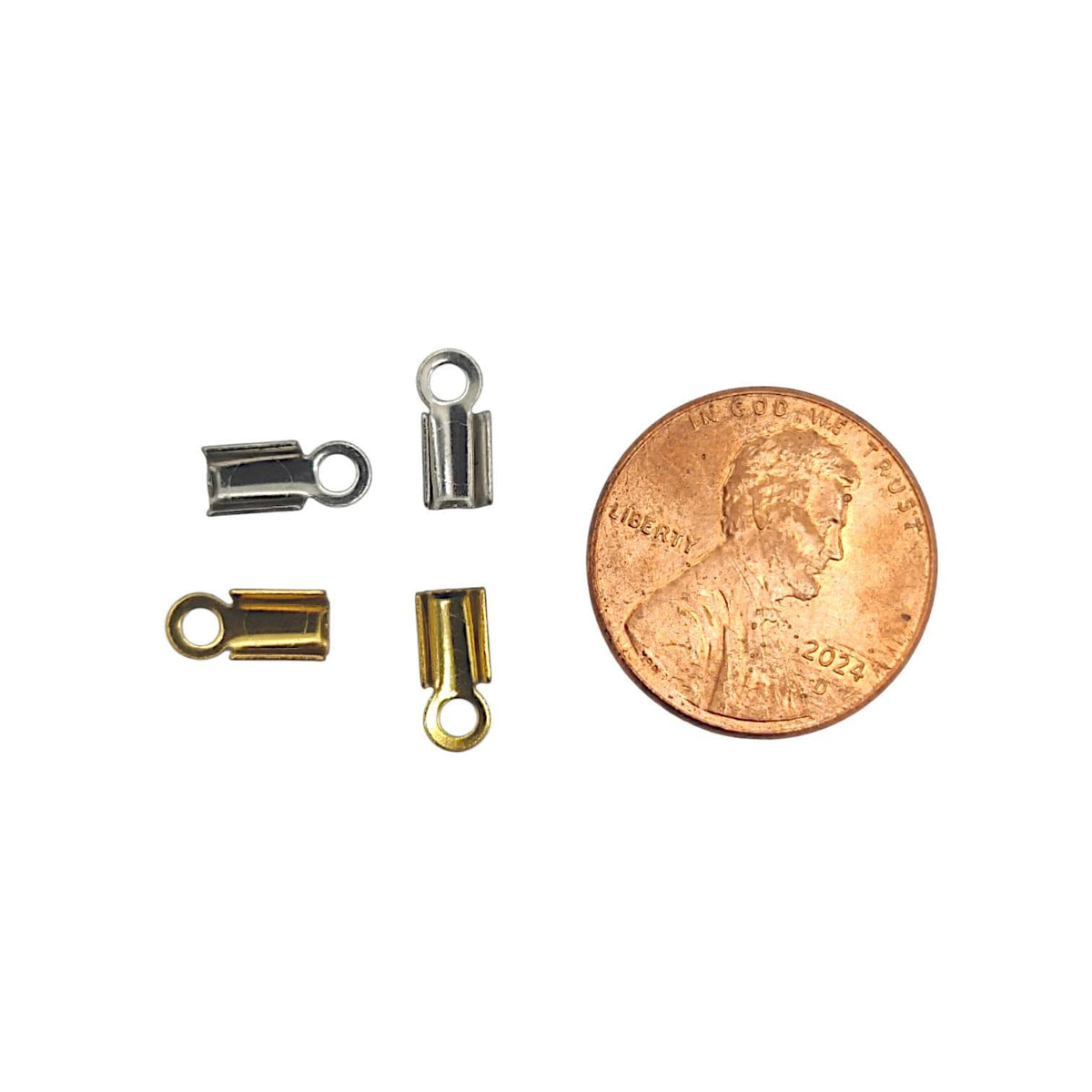 Close-up of gold and silver stainless steel fold-over cord ends next to a copper coin to show the small scale and precise sizing for jewelry findings.