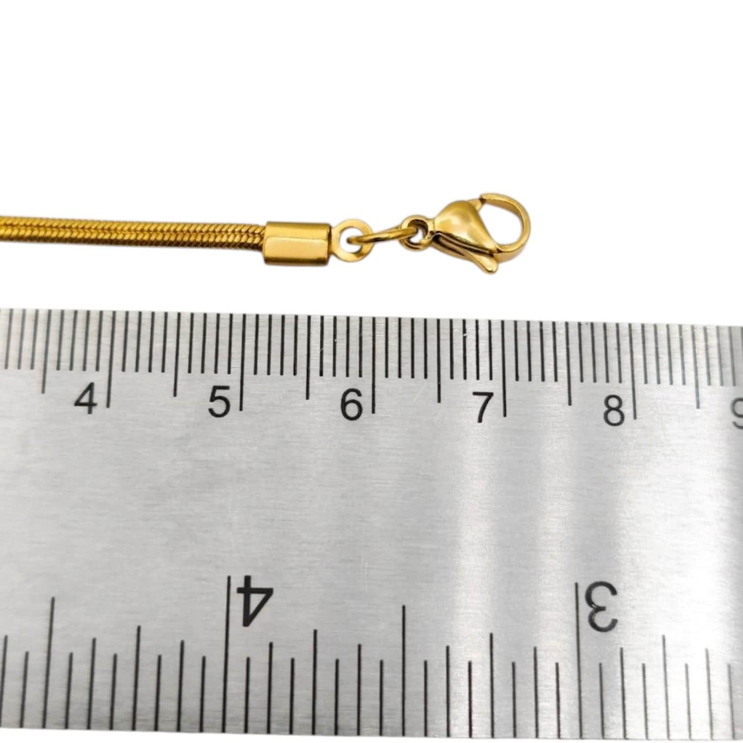 Stainless steel ribbon crimp ends laid flat against a metric ruler, clearly measuring the exact width and length of the jewelry fasteners.