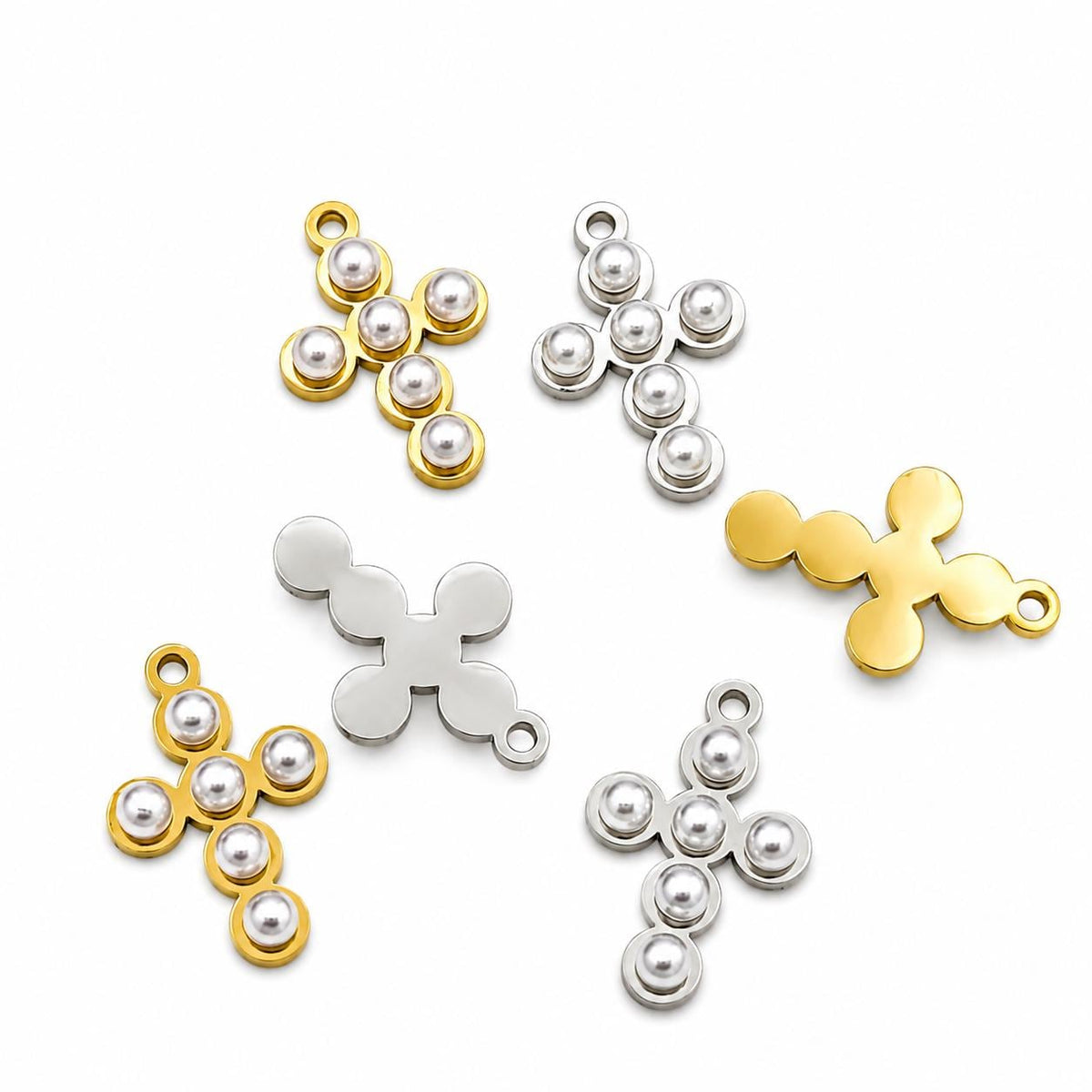 Gold and silver stainless steel cross charms with pearl accents displayed on a white background