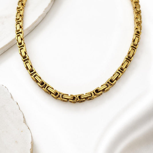 Gold stainless steel Byzantine box chain displayed in a curved necklace-style layout
