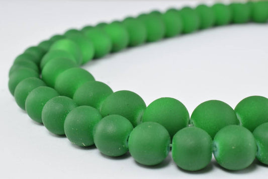 "Close-up of green matte glass beaded necklace on white background"
